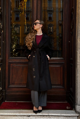 a lady in a red top, a black long wool coat and a pair of grey pants